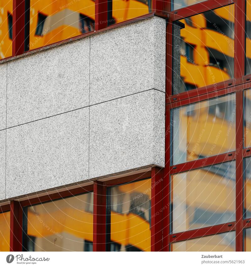 Gelbe Fassade eines Hochhauses spiegelt sich in einer Glasfassade mit roten Rahmen, dazwischen Betonelement, urbanes Wohnen gelb Spiegelung schräg wohnen