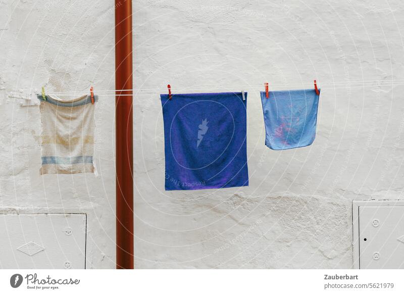Blaue und weiße Wäschestücke in quadratischer Form hänge an Leine vor weißer Wand und bilden schöne Abstraktion blau abstrakt Kunst Strukturen & Formen Fassade