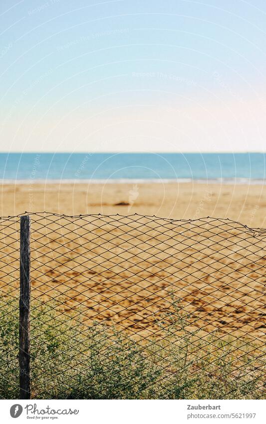 Strand, davor ein Zaun aus Maschendraht, Sehnsucht Idyll gestört Störung Realität Wirklichkeit Urlaub Barriere Meer Grenze Schutz Maschendrahtzaun Sicherheit