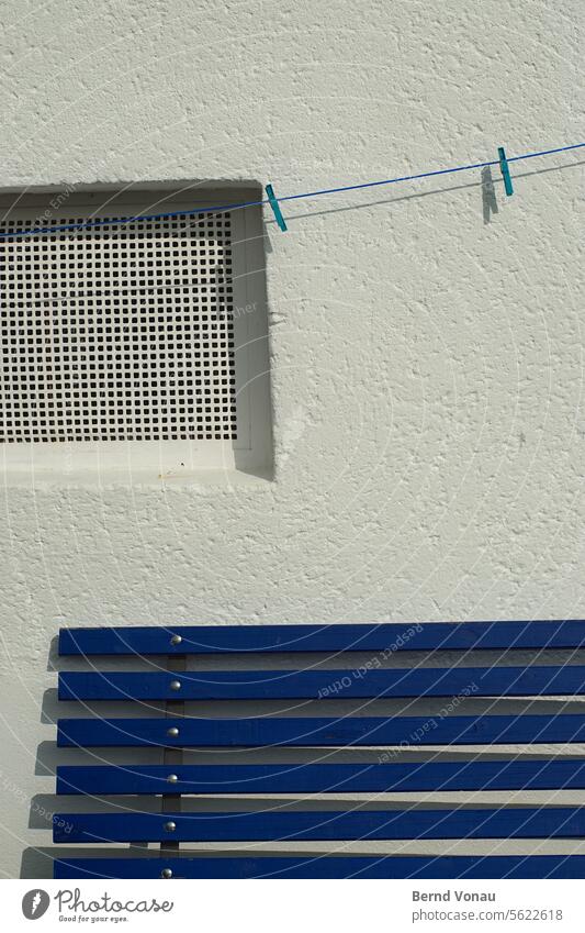 Blaue Bank und Leine vor weißer Wand Haus Mauer Sitzbank Fenster Wäscheleine Wäscheklammer Außenaufnahme Fassade Häusliches Leben aufhängen Sauberkeit