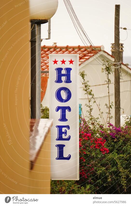 senkrechtes Schild mit Schriftzug *** HOTEL / Blumen, Strommast und Haus im Hintergrund Hotel Übernachtungsmöglichkeit Unterkunft Reisen Tourismus