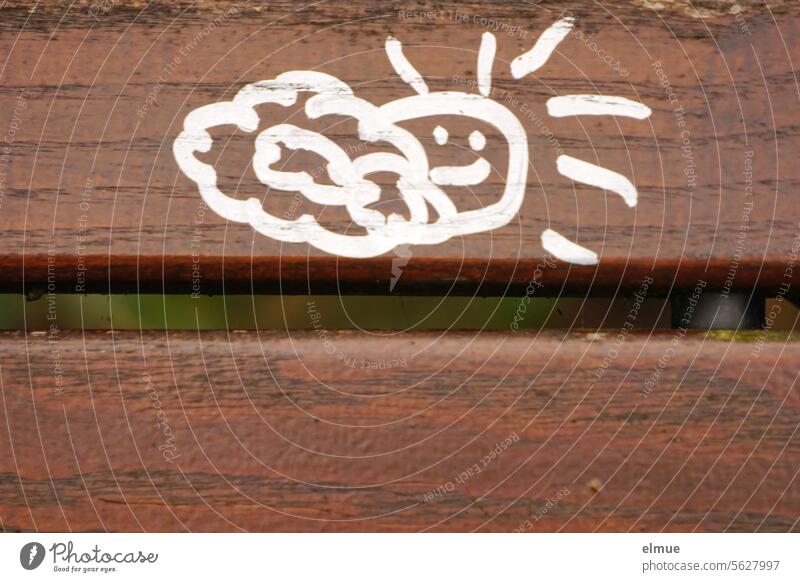 in weiß gemalte Wolke und Sonne an der Rückenlehne einer braunen Parkbank Wetter Bank Schmiererei Holzbank Sitzgelegenheit Design Blog Pause Jugendkultur