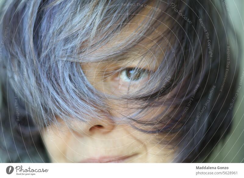 Porträt einer Frau, deren Gesicht größtenteils durch ihr Haar verdeckt ist Behaarung Frisur Wind purpur Silber grau dunkel Auge älter Hautfalten Grinsen Lächeln