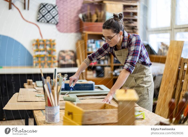 Schreinerin bemalt Möbel in ihrer Werkstatt Zimmerer wiederherstellend Schreinerei Holz Stuhl Gebäude Inszenierung Handwerk Renovierung reparierend Handwerker