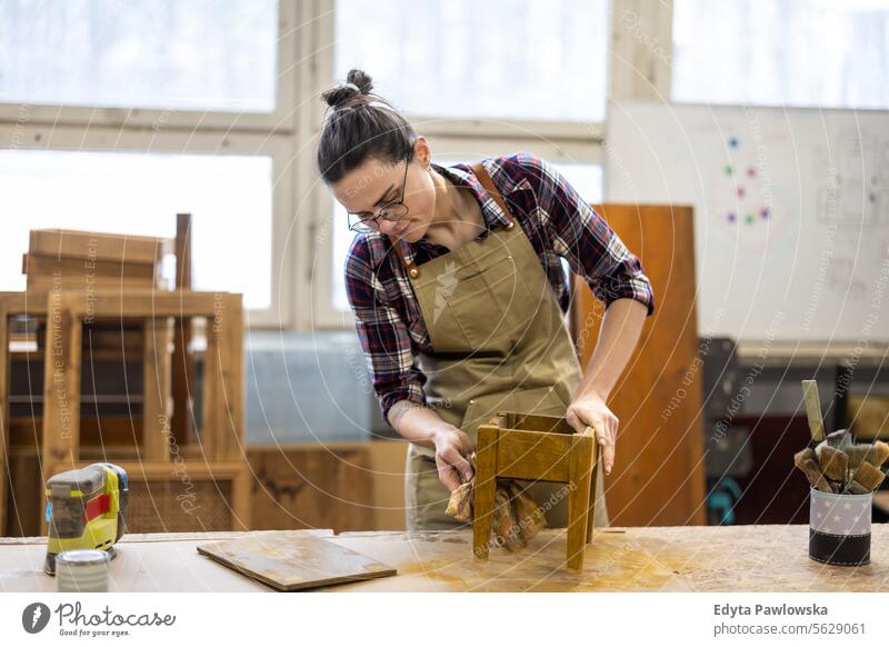 Porträt einer jungen Schreinerin bei der Arbeit in ihrer Werkstatt Möbel Zimmerer wiederherstellend Schreinerei Holz Stuhl Gebäude Herstellung Handwerk