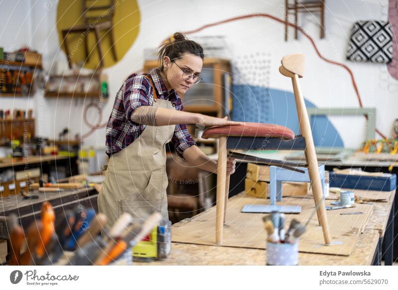 Schreinerin bei der Arbeit in ihrer Werkstatt Möbel Zimmerer wiederherstellend Schreinerei Holz Stuhl Gebäude Herstellung Handwerk Renovierung reparierend
