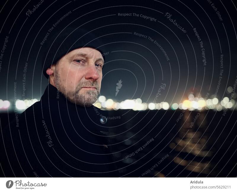 Portrait | Mann am Hafen Porträt Gesicht Blick in die Kamera Kopf Erwachsene Bart Abend Mensch streng skeptisch unfreundlich Mütze Lichter Wasser Elbe