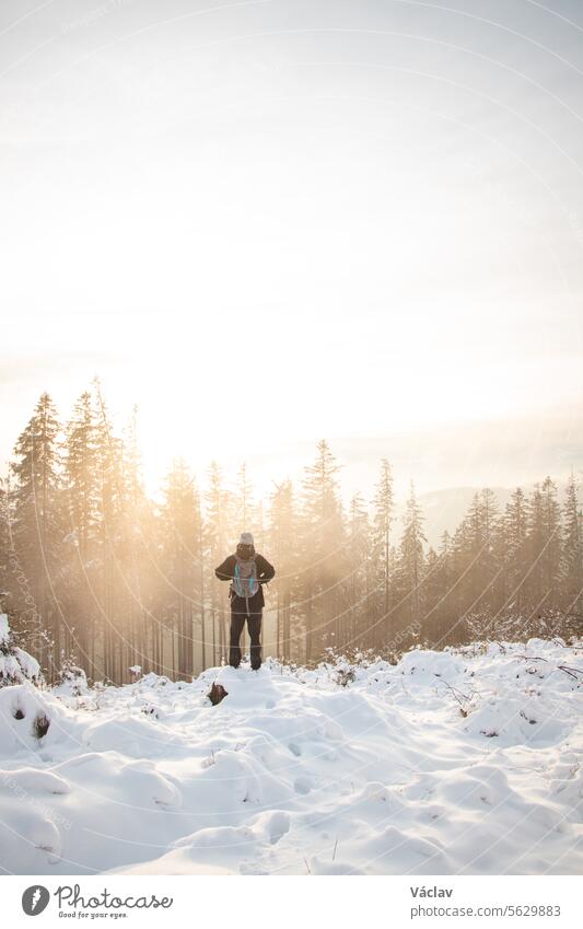 Wanderer schaut sich in der verschneiten Landschaft um. Winterwanderung durch unberührte Landschaft in den Beskiden, Tschechische Republik. Lebensstil beim Wandern. Sonnenaufgang im Winter