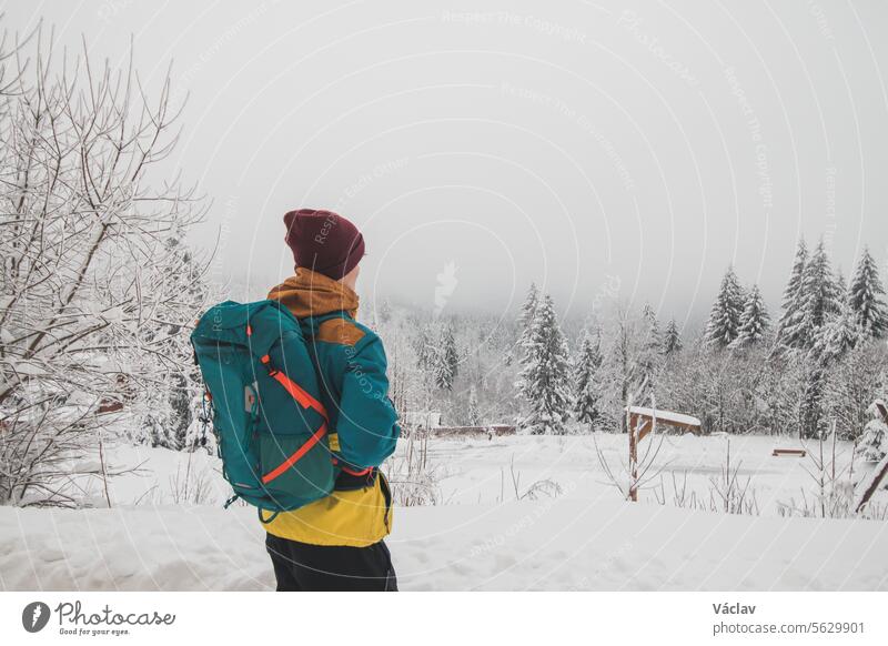 Wanderer schaut sich in der verschneiten Landschaft um. Winterwanderung durch unberührte Landschaft in den Beskiden, Tschechische Republik. Lebensstil beim Wandern
