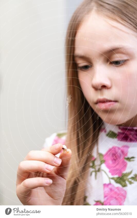 Mädchen mit Blick auf einen gezogenen Milchzahn mit Karies - Konzept der schlechten Mundhygiene Milchzähne Hohlraum Wandel & Veränderung Kind Kindheit Klinik