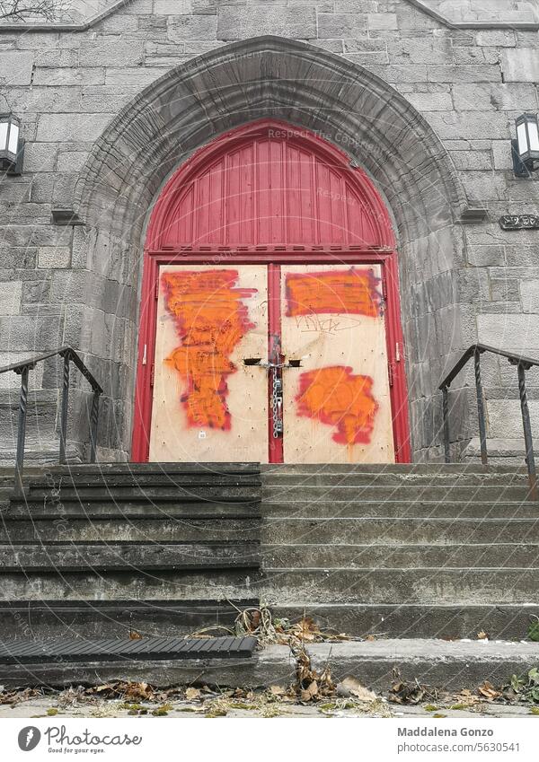 mit Brettern vernagelte Tür einer verlassenen Kirche mit abgebrochenem Graffiti und mit einer Kette verschlossen rot alt verbrettert vandalisiert anketten
