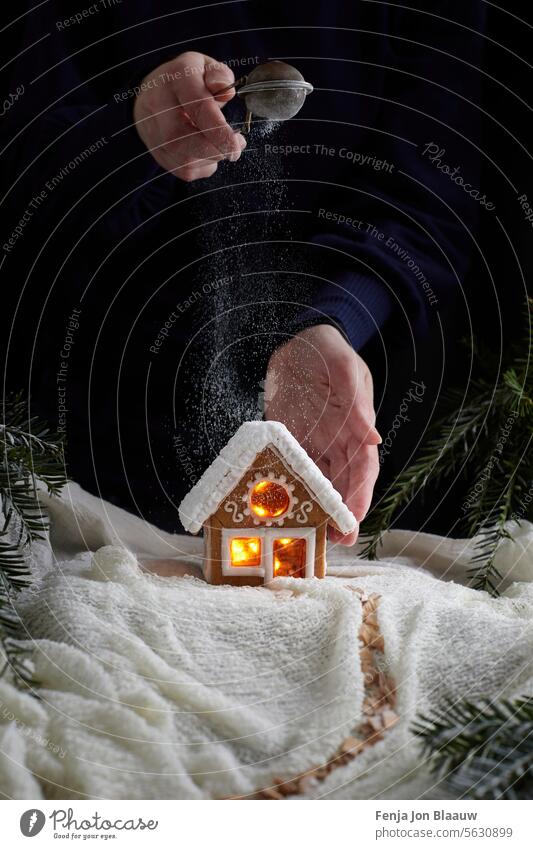 Zuckerstreuen auf einem selbstgebackenen Lebkuchenhaus in einer weihnachtlichen Umgebung im Winterwunderland Weihnachten Person Dezember weiß Stimmung