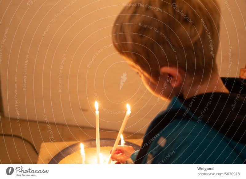 Kind das eine Kerze in einer Kirche anzündet Trauer Hoffnung Segen Religion katholisch evangelisch Gottesdienst Junge Licht Advent