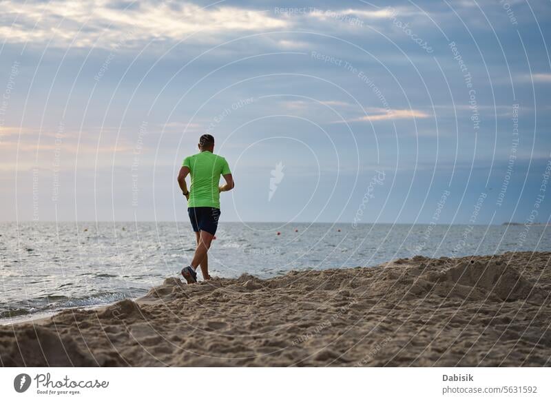 Rückenansicht eines Mannes, der am Morgen am Strand entlang joggt Sport laufen Läufer Küste MEER Joggen Lifestyle Übung Herz Training aktiv Athlet sportlich