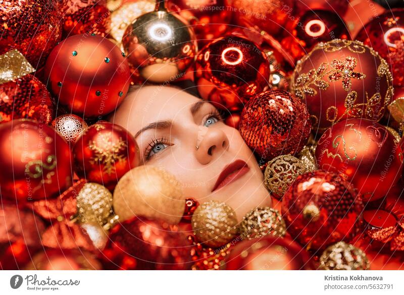 Glückliche Frau Gesicht leuchtet mit Freude in roten Weihnachtsbaum Spielzeug Kugeln. Feiertage. Ball Neujahr Dekoration & Verzierung heimwärts Ornament