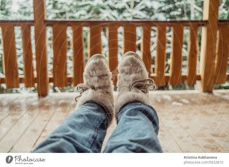 Frau Beine in Winterschuhen - Pelz trendy Stiefel auf Holz Balkon Hintergrund. Mode Fell Leder modern Schuh warm anhaben weiß bequem elegant vereinzelt neu