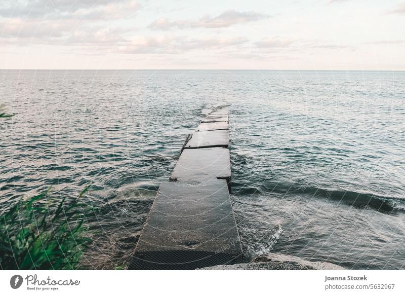 Die Wellen des Sees umgeben den Steg trist Lake Michigan Pfeiler 17 Beton düsterer Himmel grau Tristesse Große Seen Wisconsin Wasser