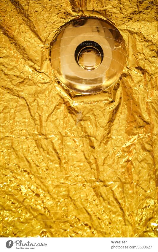 Ein goldener Knopf in einer golden verkleideten Oberfläche. Was bewirkt er? Gold Folie Blattgold edel Metall schimmern warm drücken auslösen verursachen Wirkung