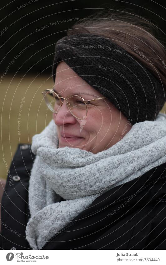 Schöne Frau grinst grinsen Grins freuen Gute Laune Winter draußen kalt eingepackt Winterkleidung Schal Stirnband Brille gold grau schwarz süß hübsch