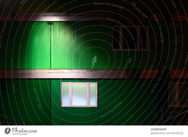 Ein grünes Containerhaus bei Nacht mit beleuchtetem Fenster Unterkunft Mehrfamilienhaus Architektur Asyl Blöcke Kasten Gebäude Lager Kapazität Großstadt