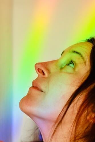 grelles, farbiges licht im gesicht einer frau. lichtstrahl regenbogen hoffnung freude glück Licht toleranz mehrfarbig Lichtbrechung Spektralfarbe