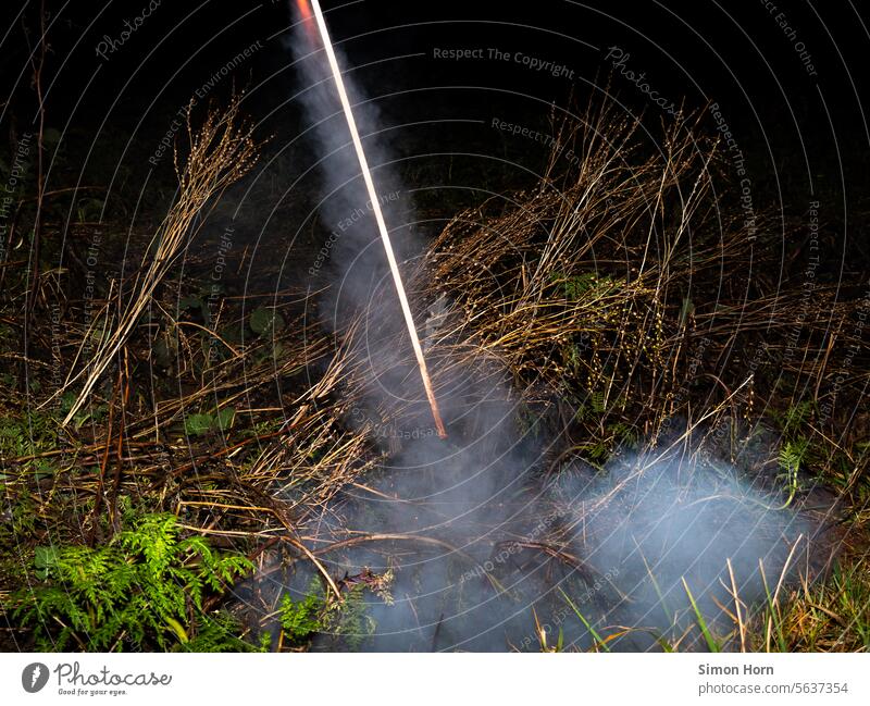 Start einer Rakete auf einem Acker Neuanfang Initiation Ritual Silvester Silvesterrakete Umweltverschmutzung Lärm Knall knallen Rauch Zündschnur zünden Feld