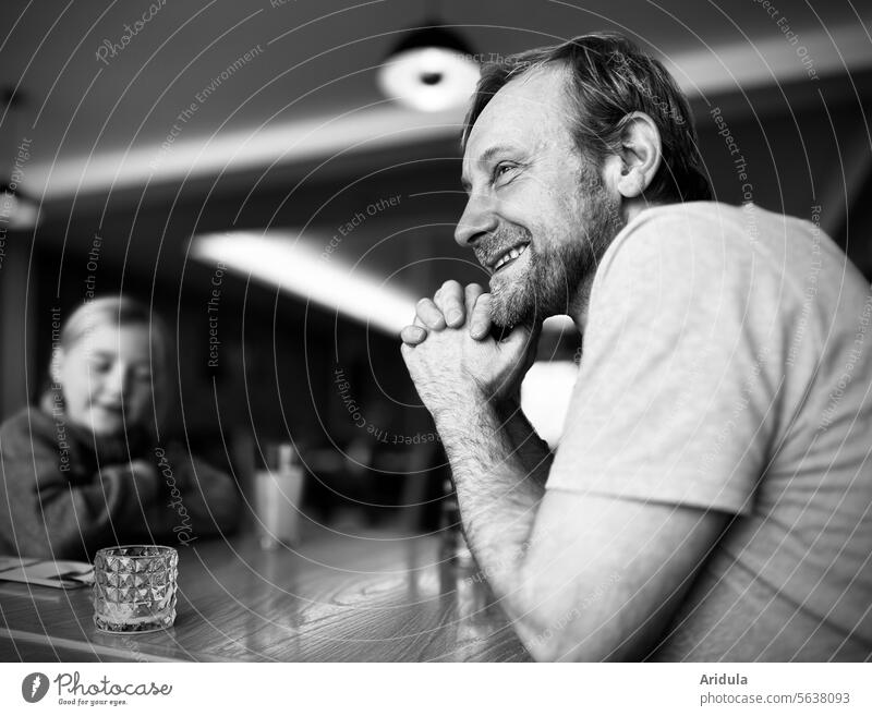 Fröhlich lächelnder Mann und ein Kind sitzen an einem Tisch s/w lachen freundlich zuhören geselliges Beisammensein Zusammensein Freude Lächeln Restaurant