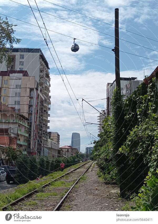 Eine Häuserschlucht in Batumi in Georgien mit einer Eisenbahnlinie und einer vorbeischwebenden Gondel! Straßenszene Mittagssonne Urlaub reisen Mittagspause