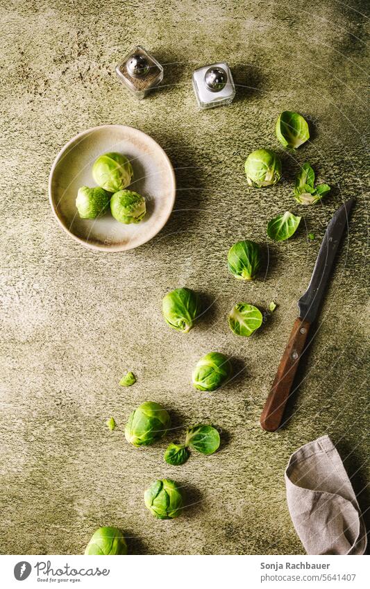 Geschälte Kohlsprossen und ein Messer auf einem grünen Tisch. roh Gemüse frisch Essen zubereiten Vegetarische Ernährung Vorbereitung Lebensmittel Zutaten