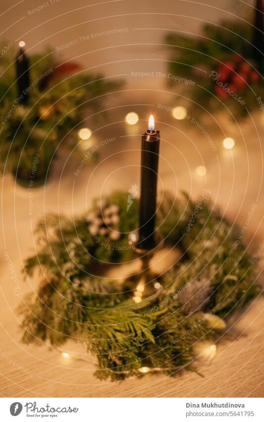 Weihnachten Blumenarrangement Kranz mit schwarz brennenden Kerze. Mittelstück festliche Dekoration mit Nadelbaumzweigen und roten Beeren. geblümt Ordnung Kerzen