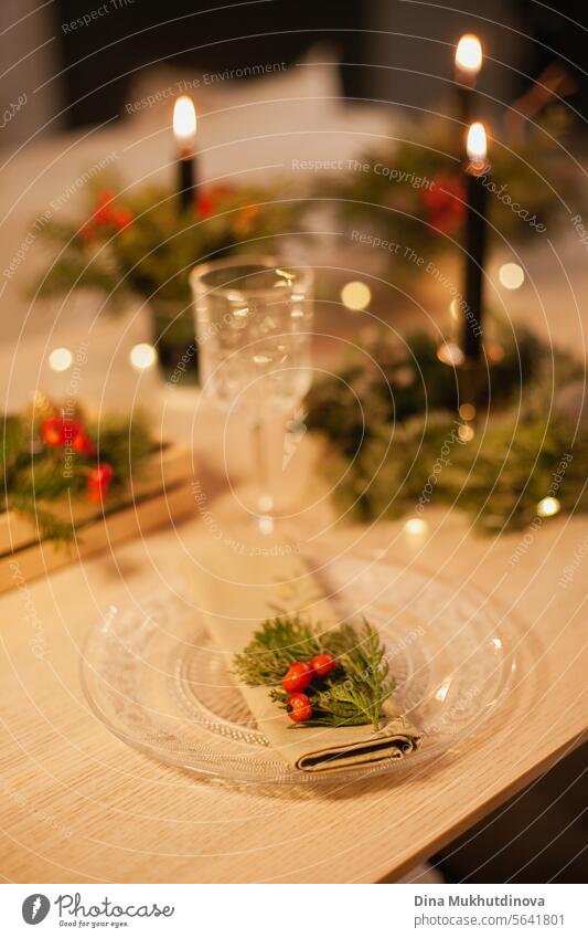 Weihnachten Blumenarrangement Tischset mit brennenden Kerze, Glas und Serviette. Mittelstück festliche Dekoration mit Nadelbaumzweigen und Beeren. geblümt