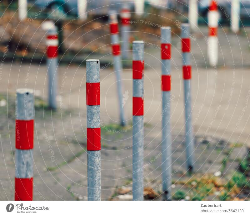 Eine Doppelreihe Pfosten mit roten Streifen auf dem Gehweg Pfahl Poller Straße Muster Reihe Linie aufgereiht stehen standhaft Fußgängerweg Schutz Sperre