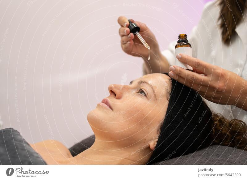 Kosmetikerin trägt Serum auf das Gesicht eines Kunden im Schönheitssalon auf Frauen Hautpflege Leckerbissen Kosmetologie Dermatologie Pflege Gesichtsbehandlung