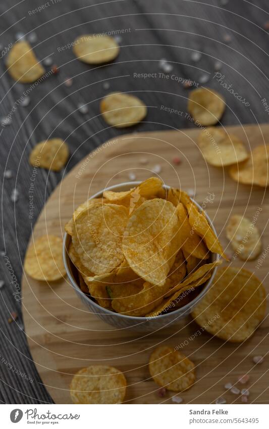 Eine Schüssel mit Kartoffelchips steht auf einem Holzbrett Chips FastFood Lebensmittel Fastfood Ernährung Essen Snack ungesund Appetit & Hunger lecker Fett