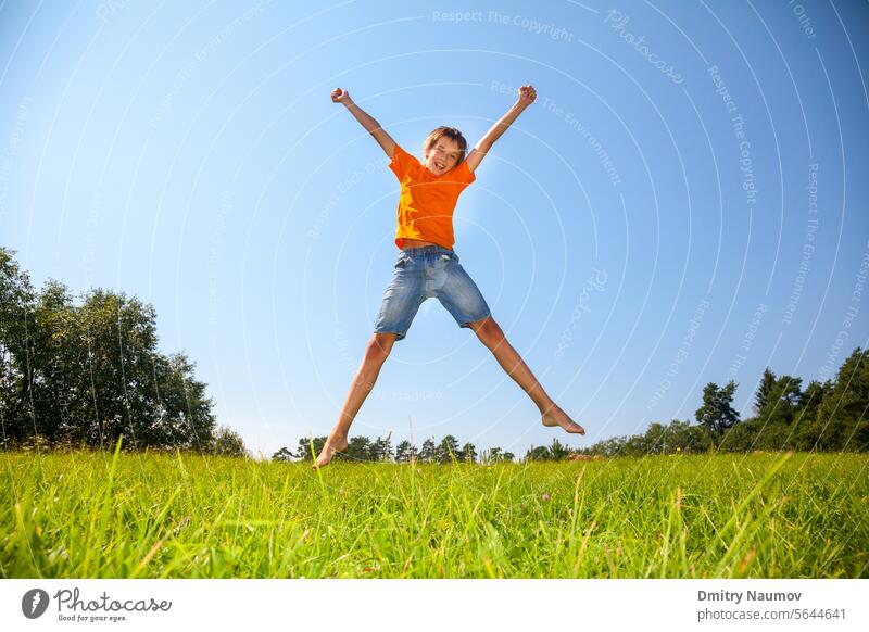 Kind springt auf der sonnigen Wiese im Freien 12-13 Jahre Positivität ausdrücken Aktivität Junge sorgenfrei Freizeitkleidung Kaukasier Kindheit Tag Emotion