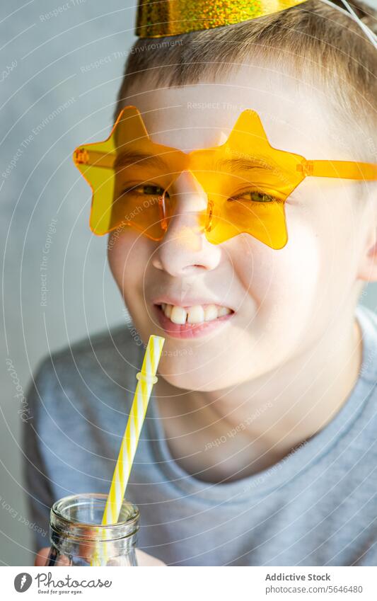 Junge genießt ein Getränk mit Sternensonnenbrille Kind Lächeln Neujahrsfest spielerisch Sonnenbrille sternförmig trinken Stroh Spaß heiter Fröhlichkeit Party
