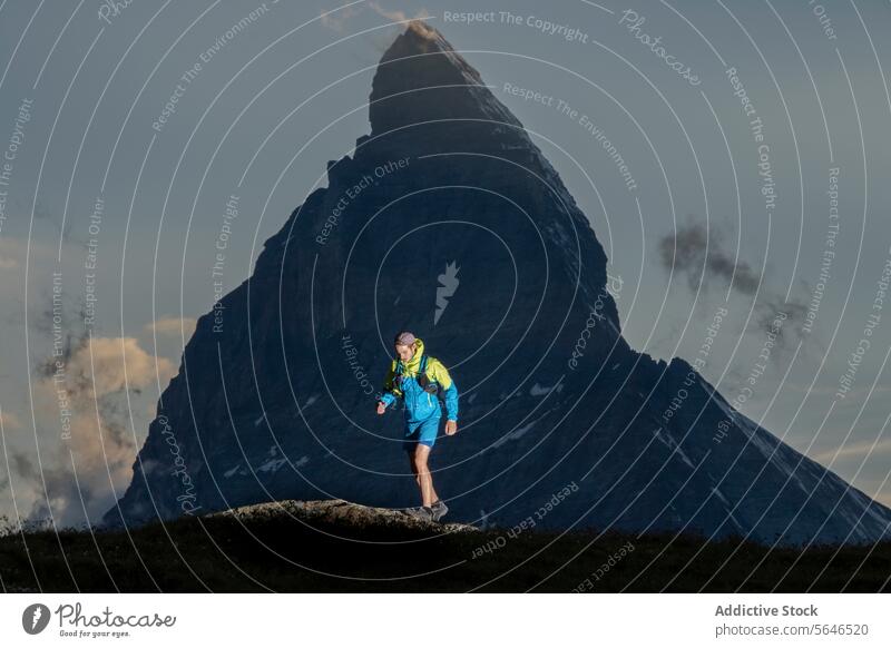 Abenteuerlicher Wanderer beim Trekking in der Nähe eines majestätischen Berggipfels Berge u. Gebirge Gipfel Silhouette Abenddämmerung Rucksack im Freien wandern
