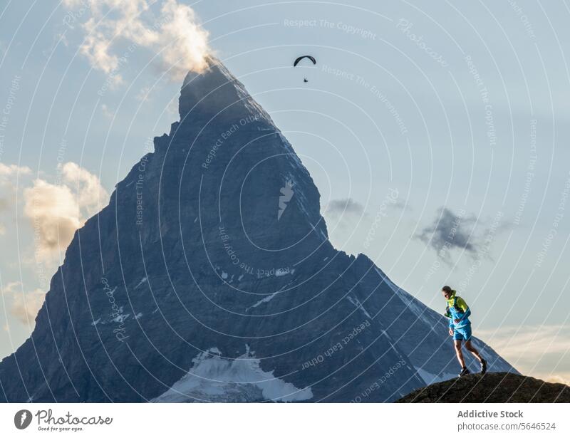 Abenteurer betrachtet Gleitschirmflieger in der Nähe des Berggipfels Berge u. Gebirge Gipfel Himmel dramatisch Ehrfurcht beobachtend pulsierend Kleidung