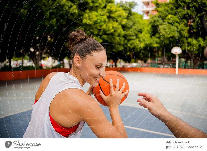 Glückliche Sportlerin spielt Basketball mit einem Freund auf dem Platz spielen Lächeln Spieler heiter Spielplatz Zusammensein Aktivität Athlet Frau Mann Ball