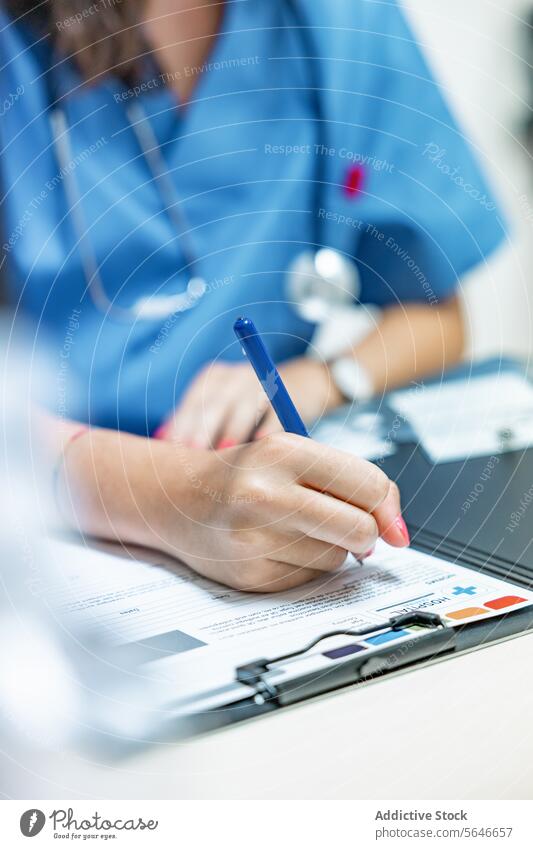 Unbekannte Ärztin sitzt am Tisch und schreibt mit einem Stift auf einem Klemmbrett Frau Arzt schreiben Smartphone Zwischenablage Stethoskop professionell