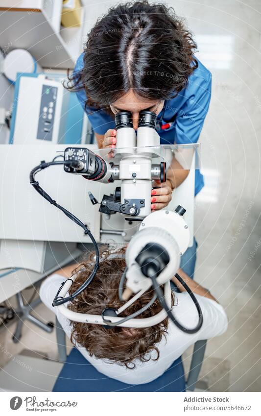 Junge Ärztin untersucht das Auge eines unkenntlichen Mannes in einer Klinik in Lichtern Frau Arzt geduldig Uniform Stethoskop prüfen Spaltlampen-Biomikroskop