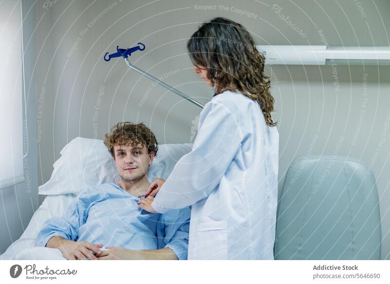 Ein Arzt untersucht einen auf dem Bett liegenden Patienten mit einem Stethoskop in einer Klinik Mann geduldig Krankenpfleger prüfen untersuchen Krankenhaus