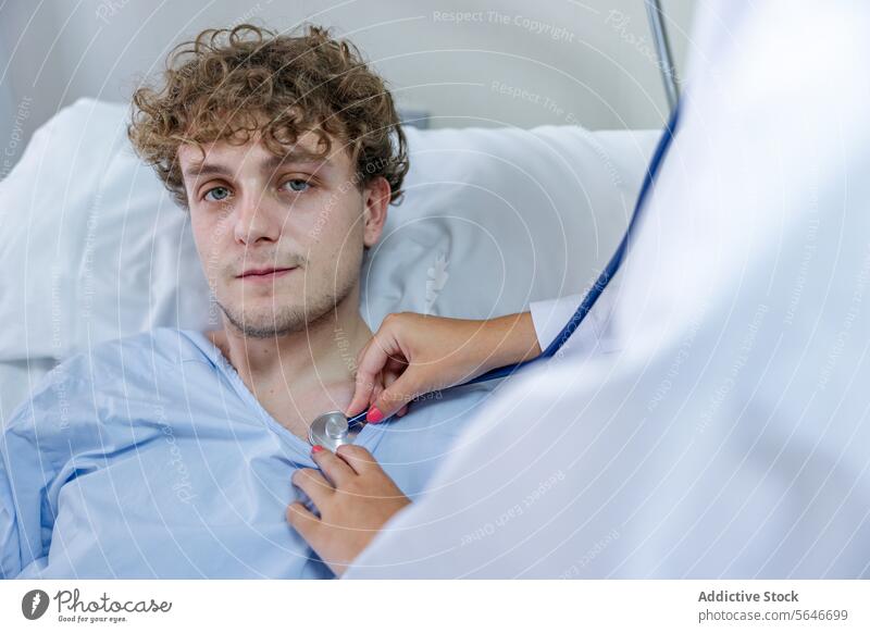 Ein Arzt untersucht einen auf dem Bett liegenden Patienten mit einem Stethoskop in einer Klinik Mann geduldig Krankenpfleger prüfen untersuchen Krankenhaus