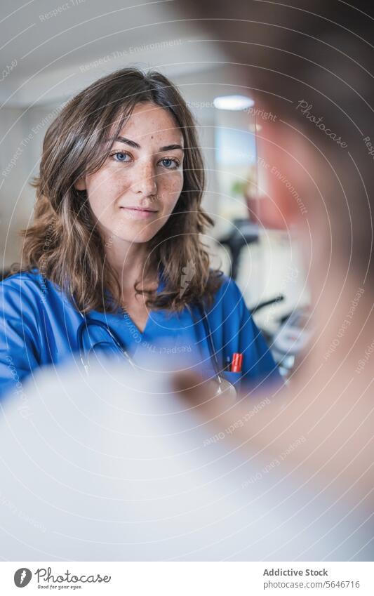 Lächelnde junge Ärztin schaut in die Kamera, während sie im Krankenhaus steht Frau Arzt Uniform medizinisch Gang Klinik Spezialist Krankenpfleger