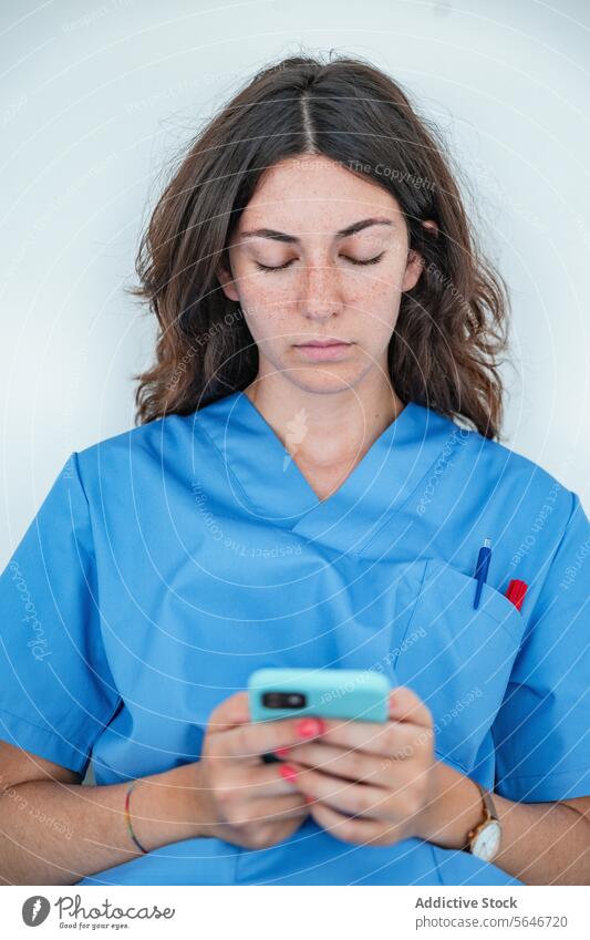 Junge Krankenschwester, die auf einer Bank sitzend auf ihrem Smartphone surft Frau Krankenpfleger Krankenhaus benutzend Browsen Uniform Medizin