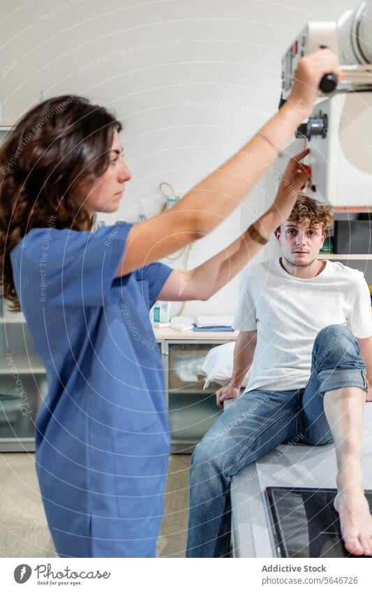 Junge Technikerin justiert Röntgengerät zum Scannen eines Patienten, der auf einem Bett in einer Klinik sitzt Frau Krankenpfleger geduldig Mann Röntgenbild