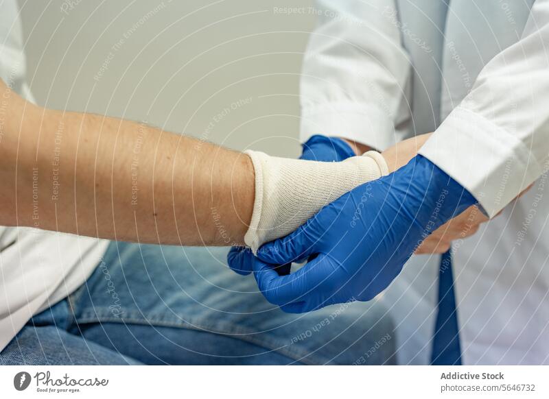 Crop-Arzt beim Anlegen eines elastischen Schutzbandes in den Händen eines Patienten in einer Klinik Band Handschuh geduldig behüten Gesundheitswesen Krankenhaus