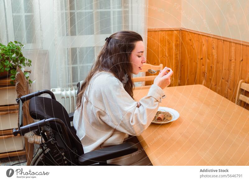 Frau genießt Mahlzeit zu Hause im Rollstuhl speisend heimwärts Genuss Zugänglichkeit Tisch Essen Inhalt Selbstständigkeit angepasst Lifestyle Lebensmittel