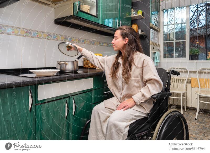 Frau im Rollstuhl kocht in zugänglicher Küche Essen zubereiten Zugänglichkeit ungültig Anpassung Selbstständigkeit heimwärts Innenbereich Lifestyle Behinderung