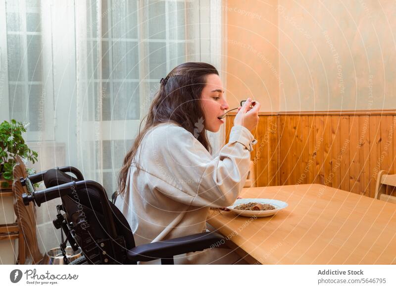 Frau genießt Mahlzeit zu Hause im Rollstuhl speisend heimwärts Genuss Zugänglichkeit Tisch Essen Inhalt Selbstständigkeit angepasst Lifestyle Lebensmittel